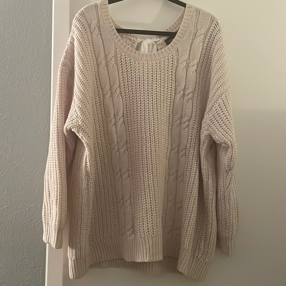 Cream cable knit sweater with bow tie embellishment in back